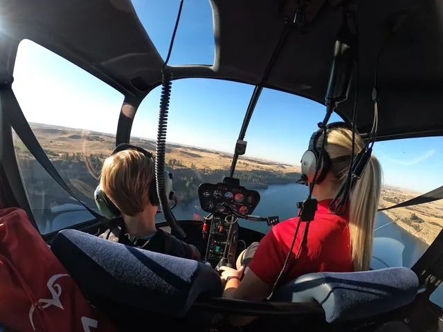 Cockpit view with Amy at the controls over a river valley and golden hills.